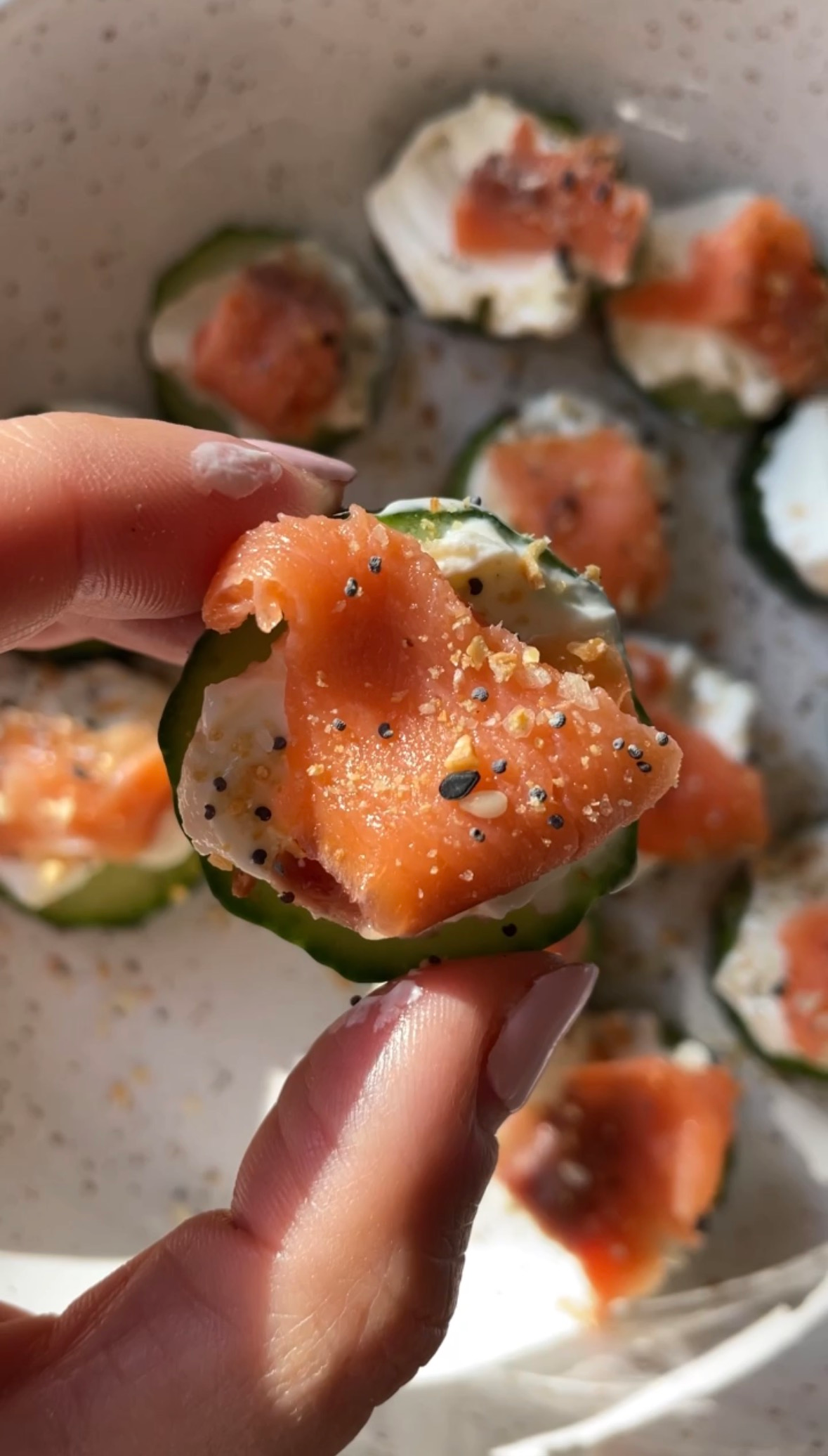 hand holding a cucumber salmon bite with everything bagel seasoning