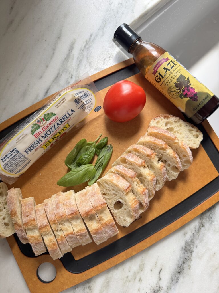 simple caprese crostini on a wooden serving board with balsamic glaze drizzle