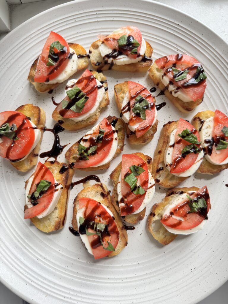 overhead view of simple caprese crostini with mozzarella, tomatoes and fresh basil