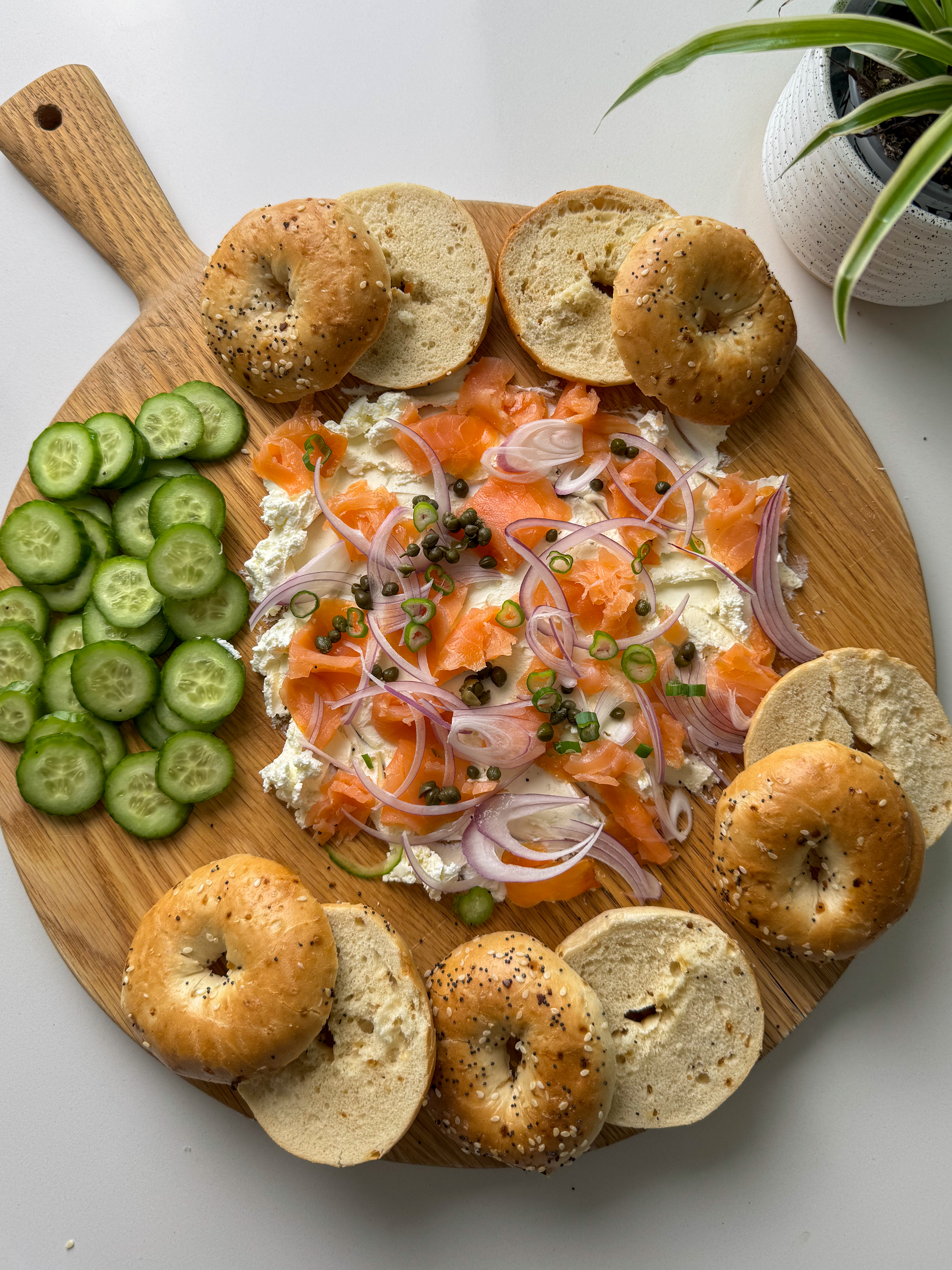 complete lox bagel board with toasted bagels, cucumber, smoked salmon, cream cheese, capers, and red onion