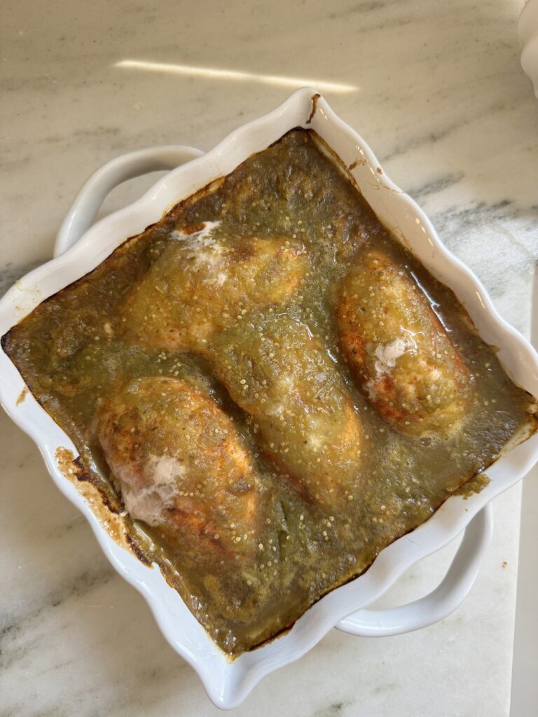 Chicken breasts baked in salsa verde sauce in a white ceramic baking dish