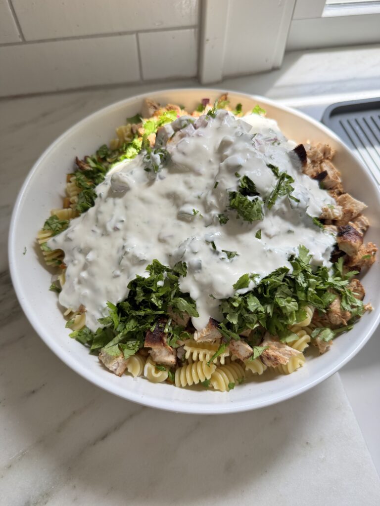 Close up of Mexican streetcorn pasta salad showing rotini pasta with charred corn, jalapeños, red onion and crumbled feta
