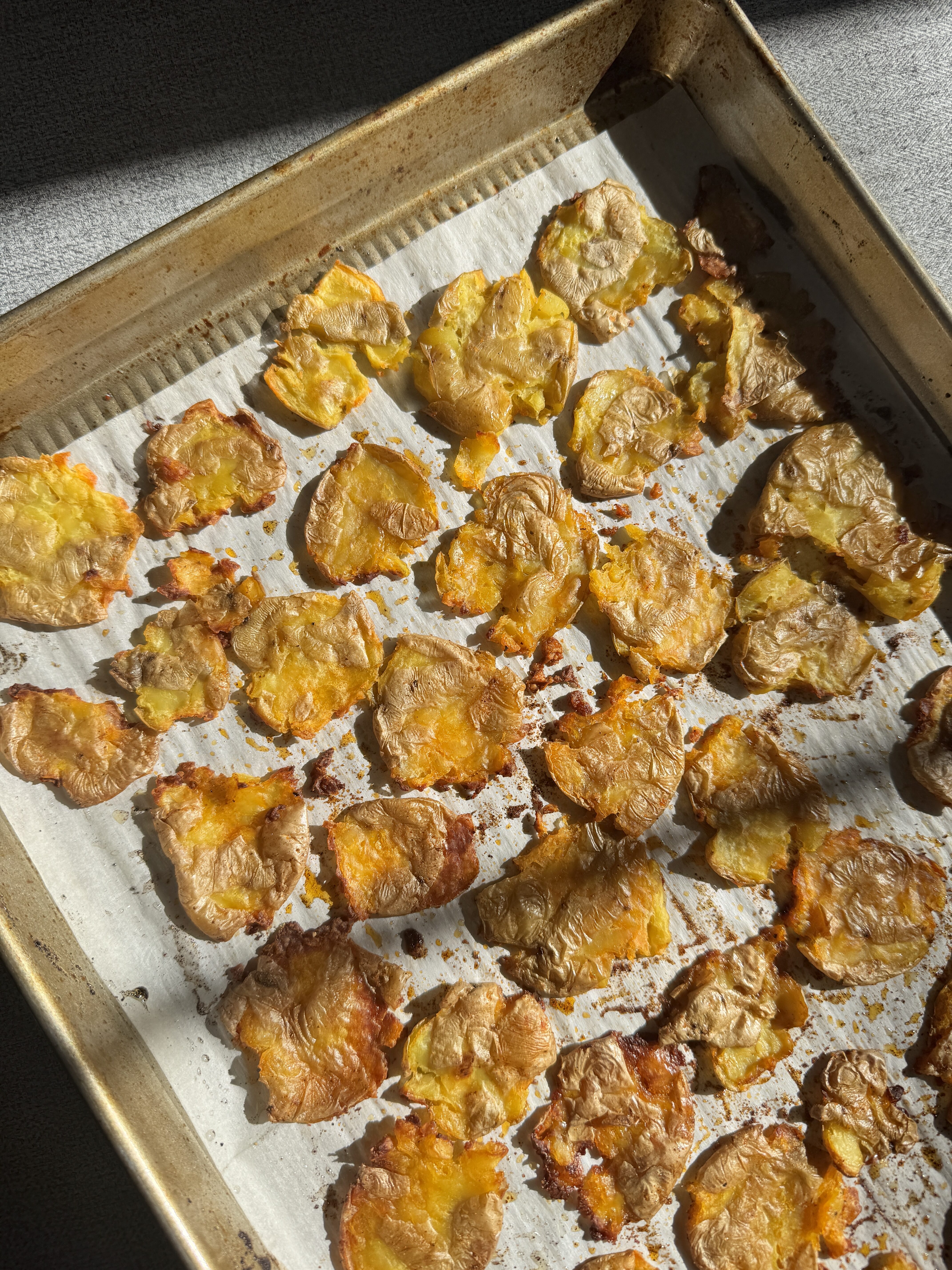Golden crispy smashed baby potatoes fresh out of the oven on a baking sheet