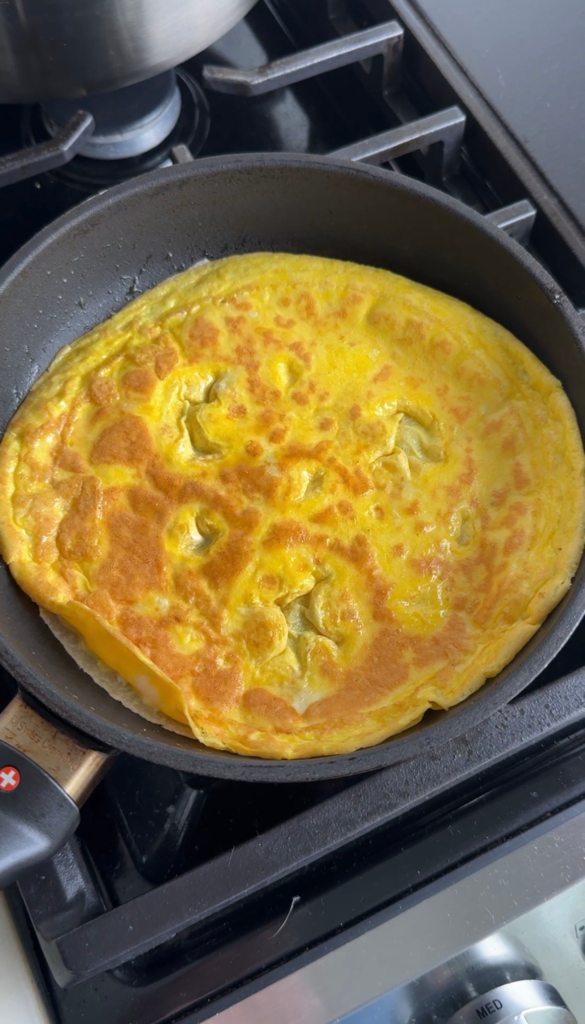 egg tortilla wrap cooking in a skillet on the stovetop