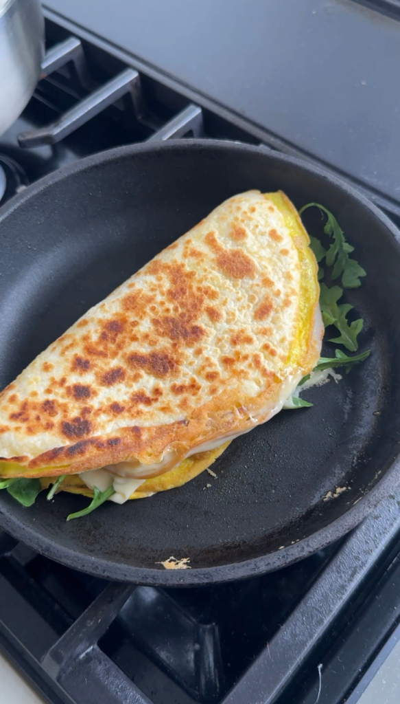 egg tortilla wrap folded in half cooking golden and crispy in a cast iron skillet