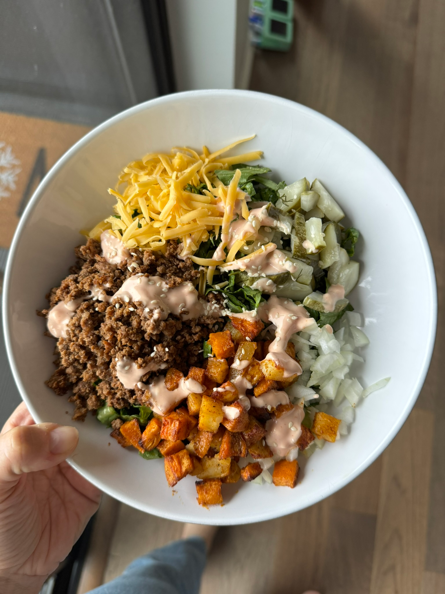 Cheeseburger bowl drizzled with creamy special sauce and sesame seeds