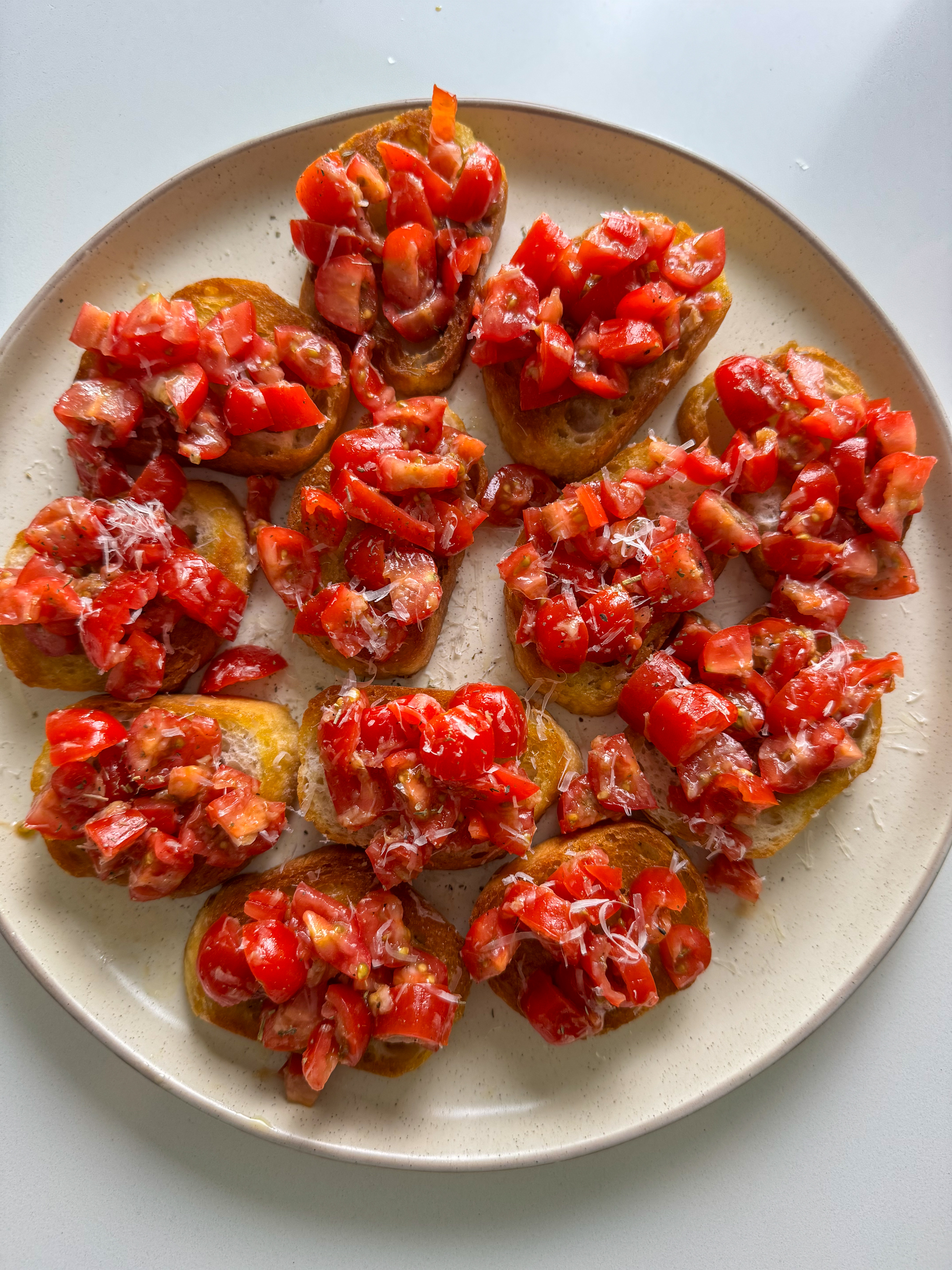 Simple bruschetta with cherry tomatoes, basil, and Parmesan on crispy crostini