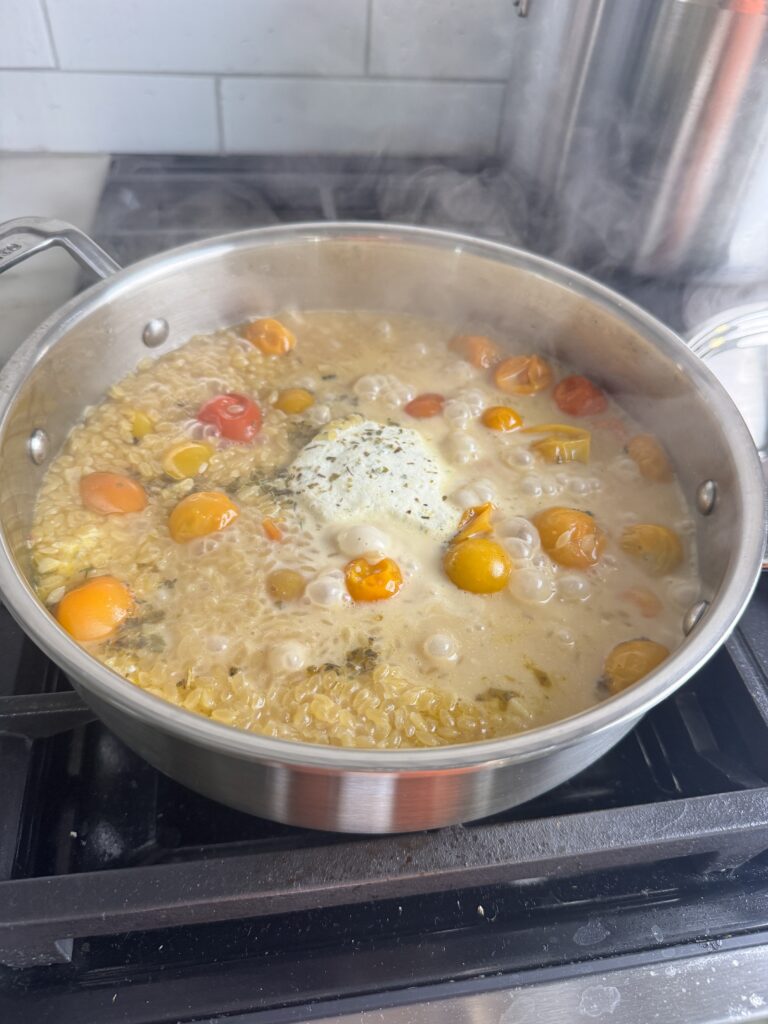 Orzo, cherry tomatoes, and Boursin simmering in broth in one pot