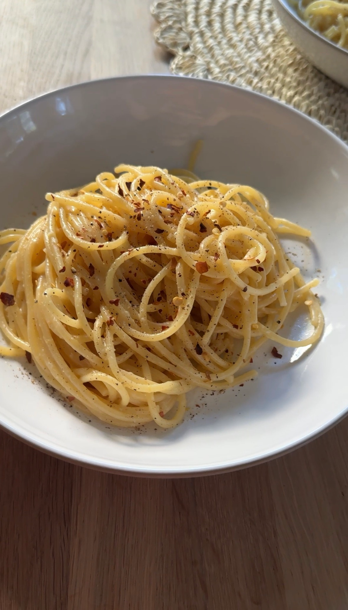 One pot pasta al limone in a white bowl topped with red chili flakes and black pepper