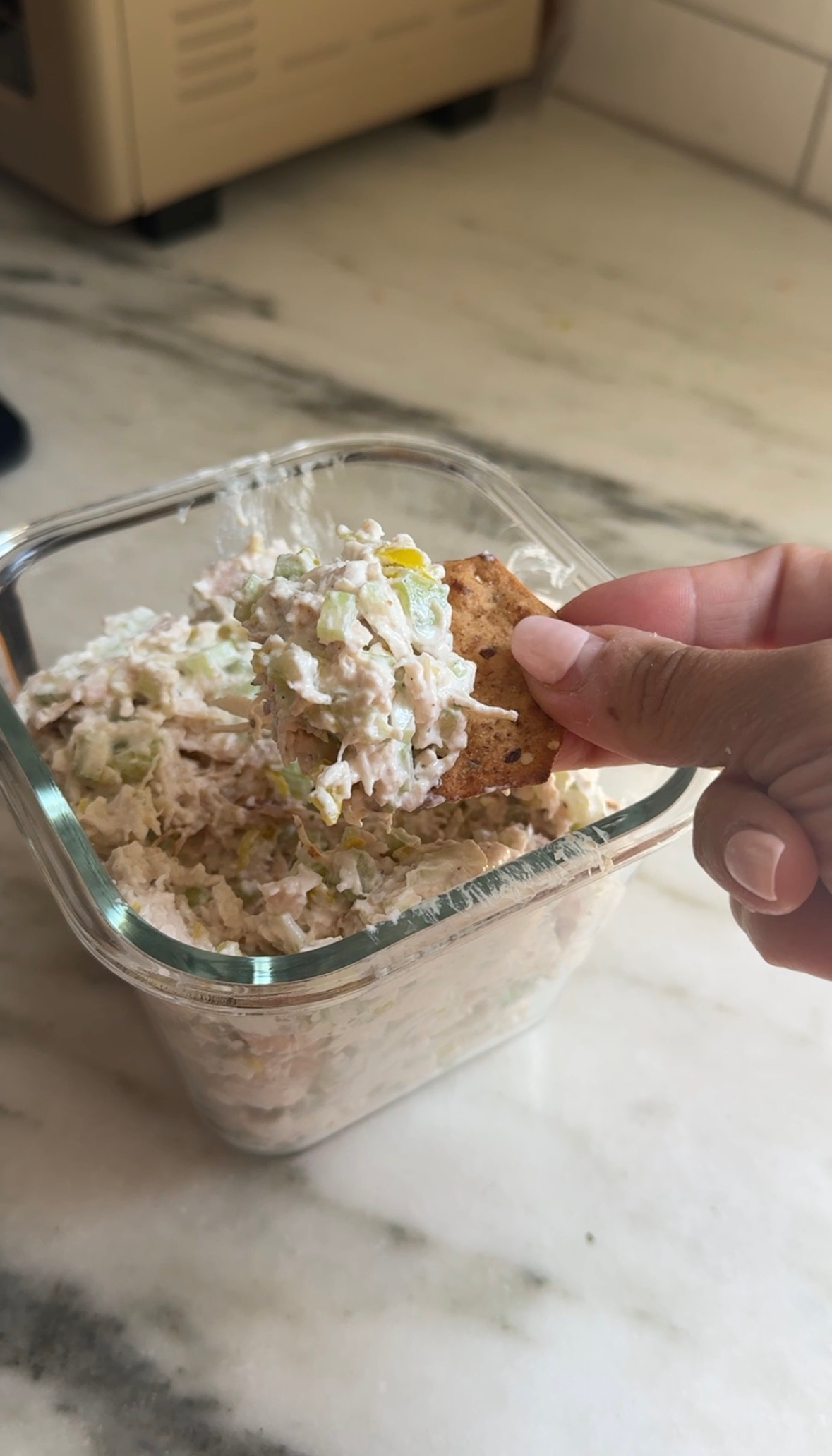 Pepperoncini chicken salad in a glass container being scooped up with a cracker