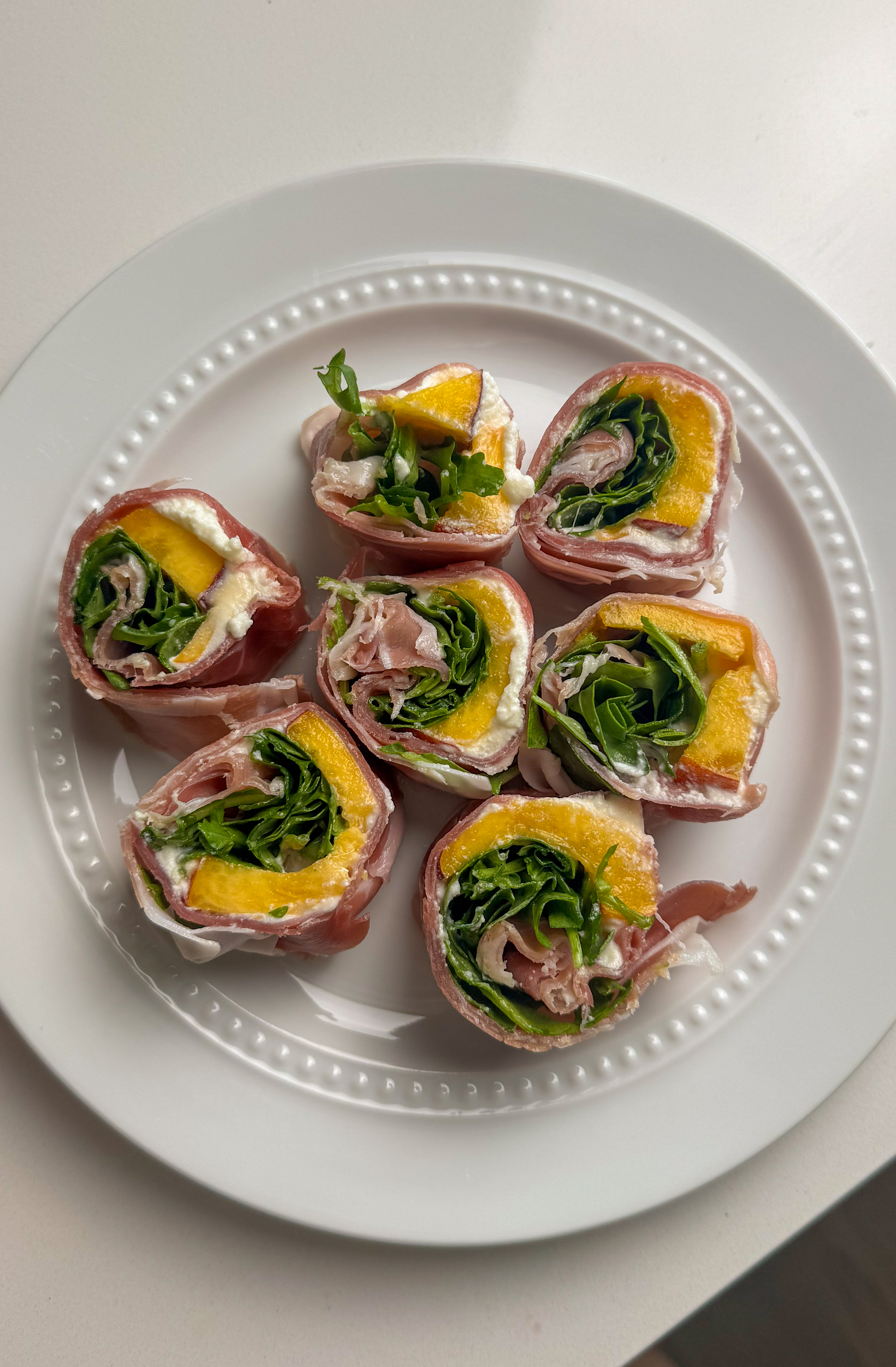 Prosciutto peach ricotta roll ups drizzled with hot honey