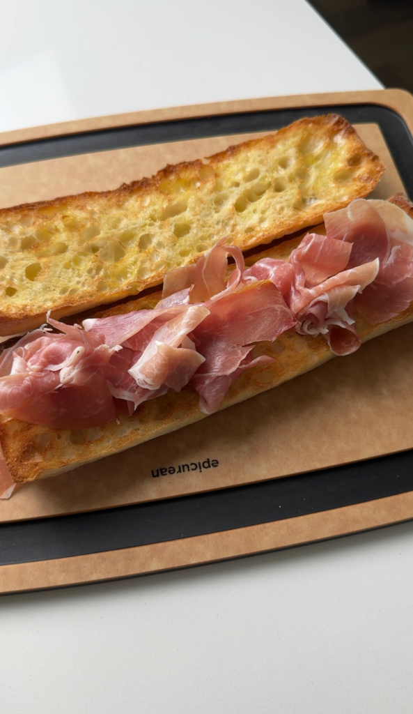Prosciutto layered on a toasted baguette for a peach prosciutto sandwich
