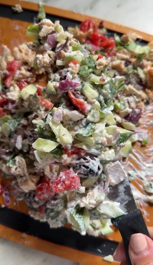 Chopped Mediterranean chicken wrap filling with chicken, veggies, and tzatziki on a cutting board