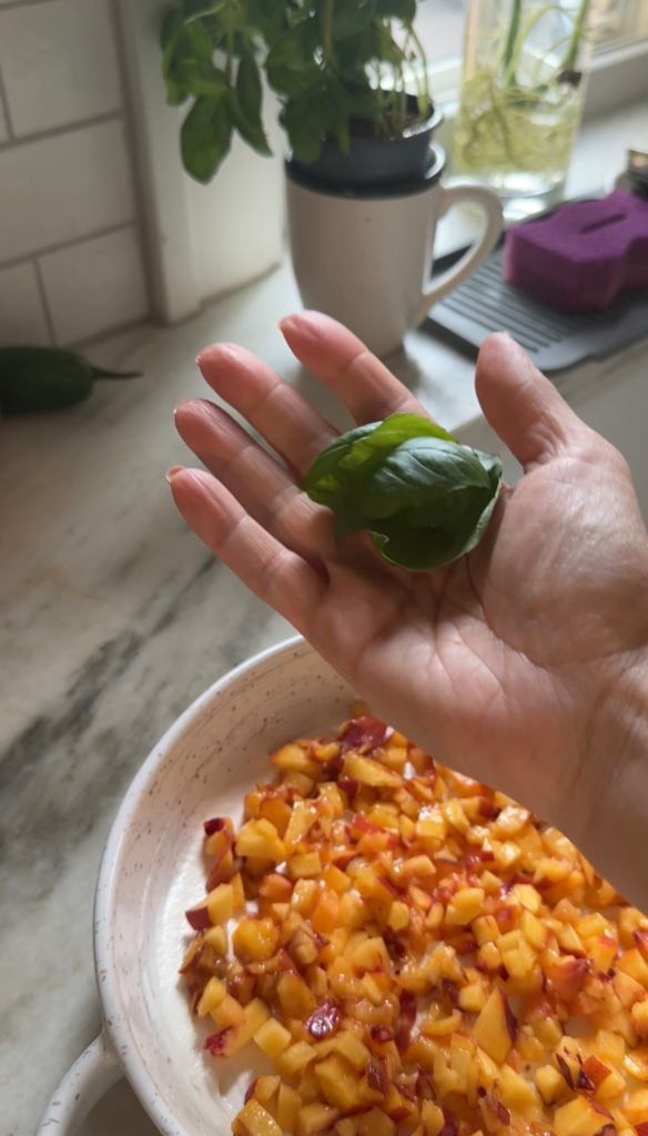 Adding fresh basil to peach dip topped with diced peaches