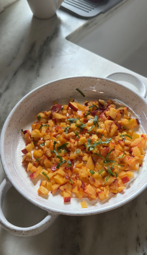 Easy peach dip with goat cheese, diced peaches, and fresh basil in a serving dish