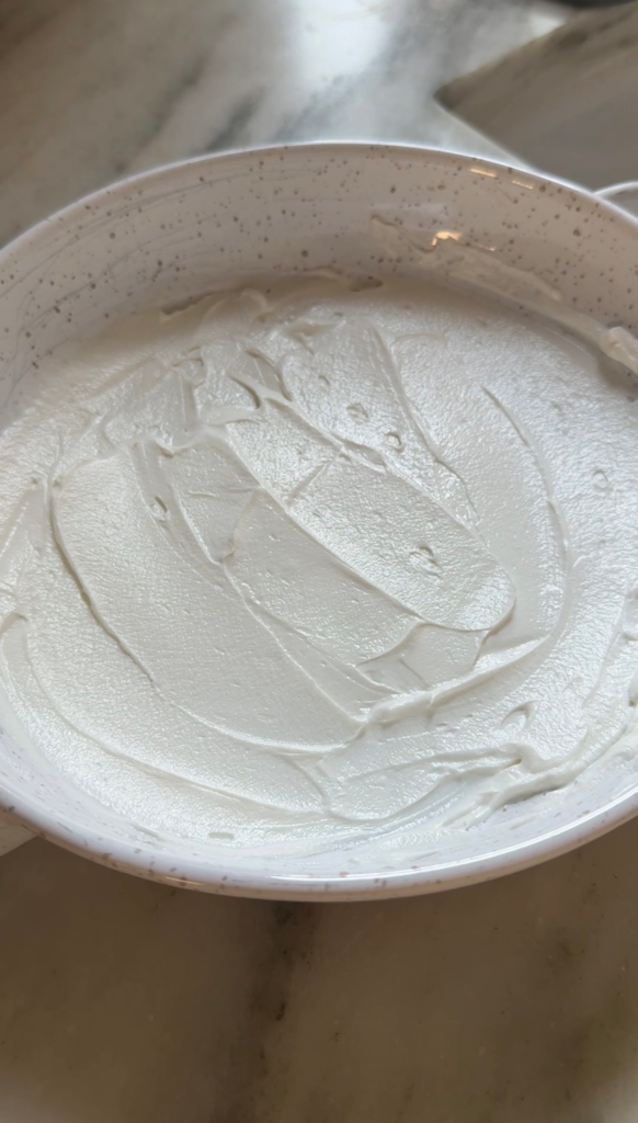 Creamy goat cheese spread in a thin layer in a serving dish for peach dip