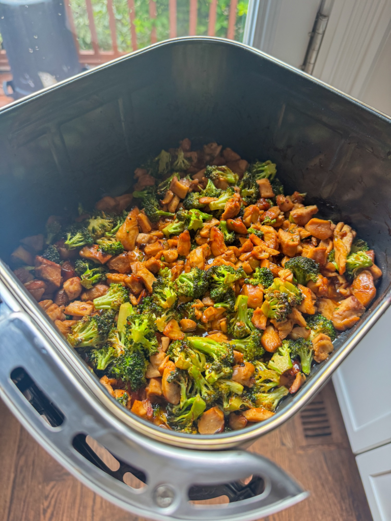 Diced teriyaki chicken and broccoli tossed together in an air fryer basket