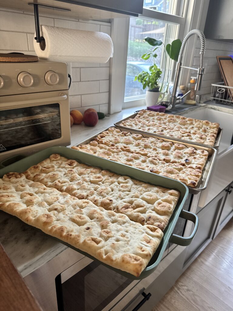 Five baked flatbread pizzas on sheet pans for a party