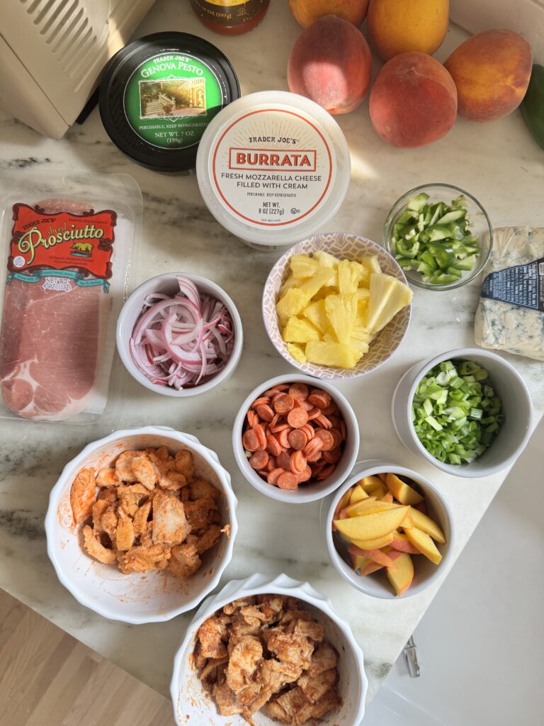 Ingredients for a flatbread pizza party including burrata, prosciutto, peaches, and toppings