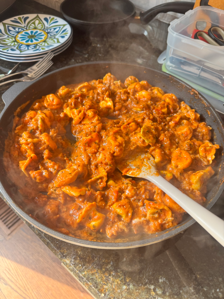 Creamy sausage tortellini in a skillet with a glossy pink sauce