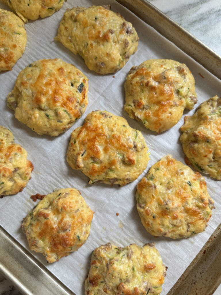 Golden baked protein zucchini sausage biscuits on a parchment lined baking sheet