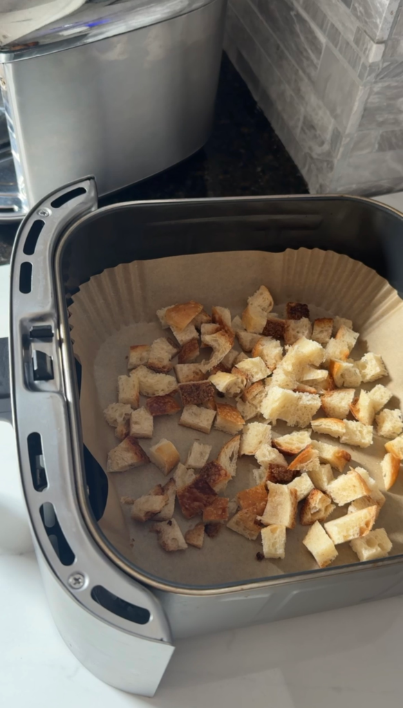 Seasoned bread cubes in an air fryer basket before cooking