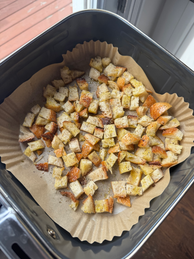 Golden crispy croutons in an air fryer basket