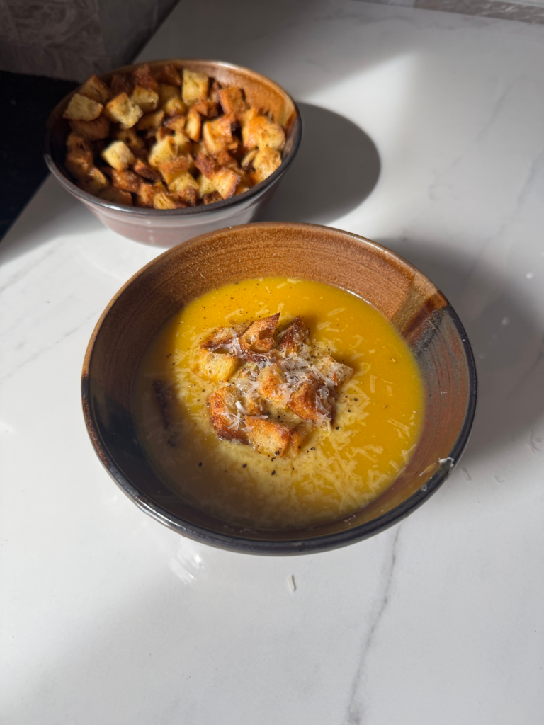 A bowl of vegetable soup topped with croutons next to a bowl of air fryer croutons