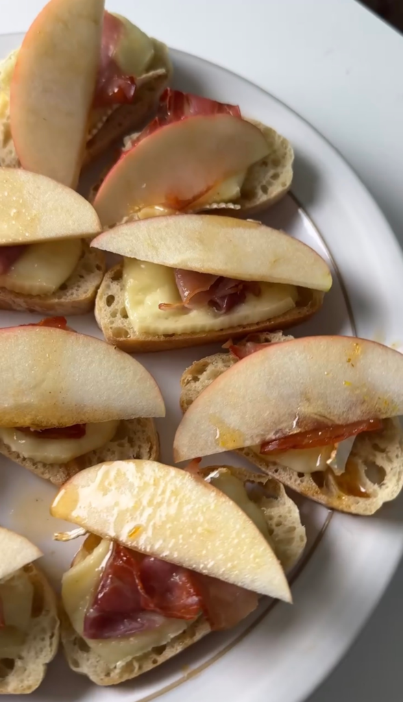 A plate of apple and brie crostini with prosciutto and hot honey