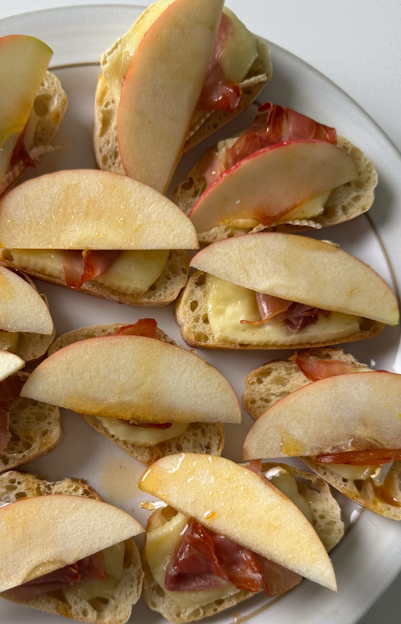 Apple and brie crostini on a plate drizzled with hot honey