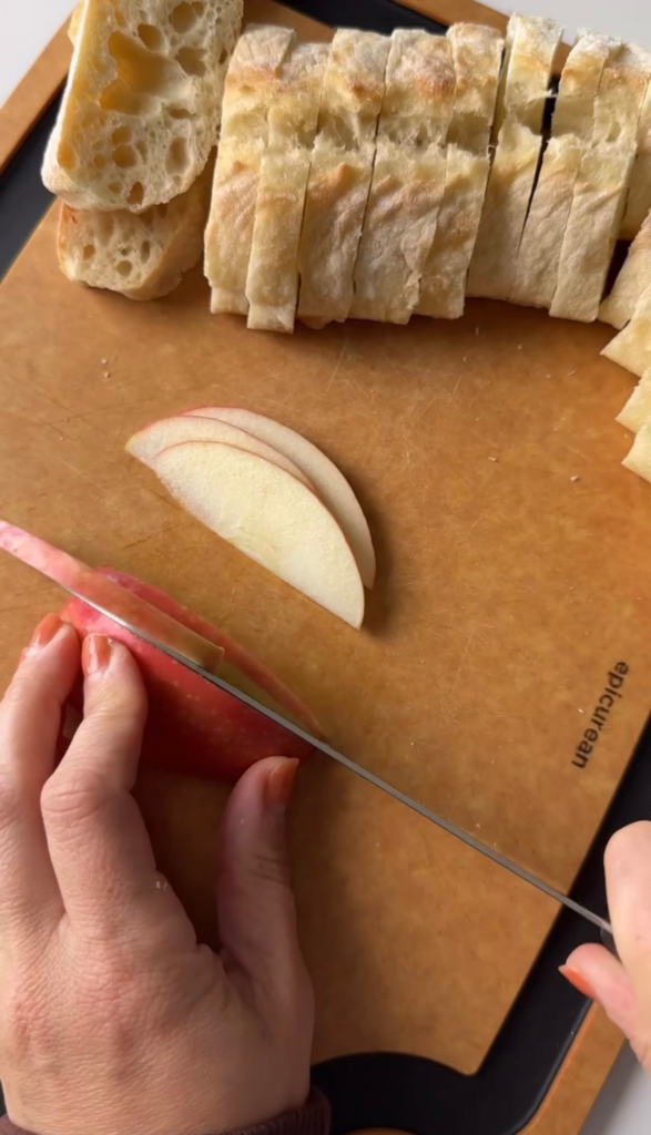 Sliced baguette and fresh apple slices on a cutting board