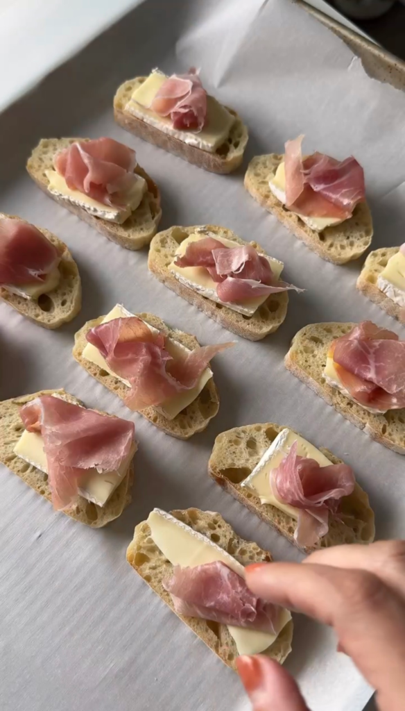 Brie-topped baguette slices with prosciutto before baking