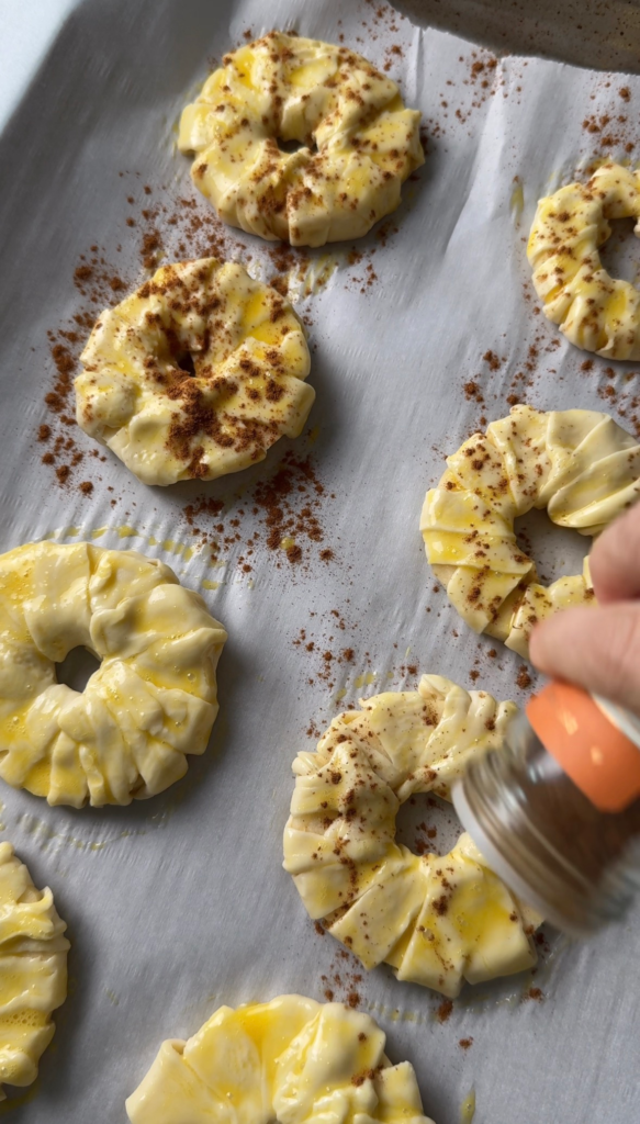 Sprinkling cinnamon sugar over the donuts before baking