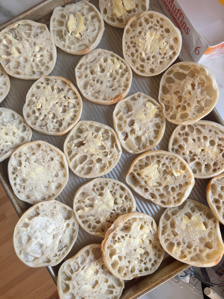 Split and buttered English muffins on a baking sheet