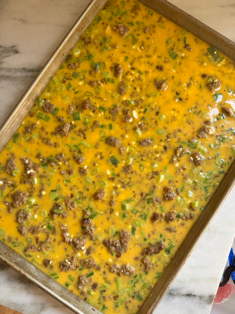 Sausage and scallion egg mixture poured onto a sheet pan before baking