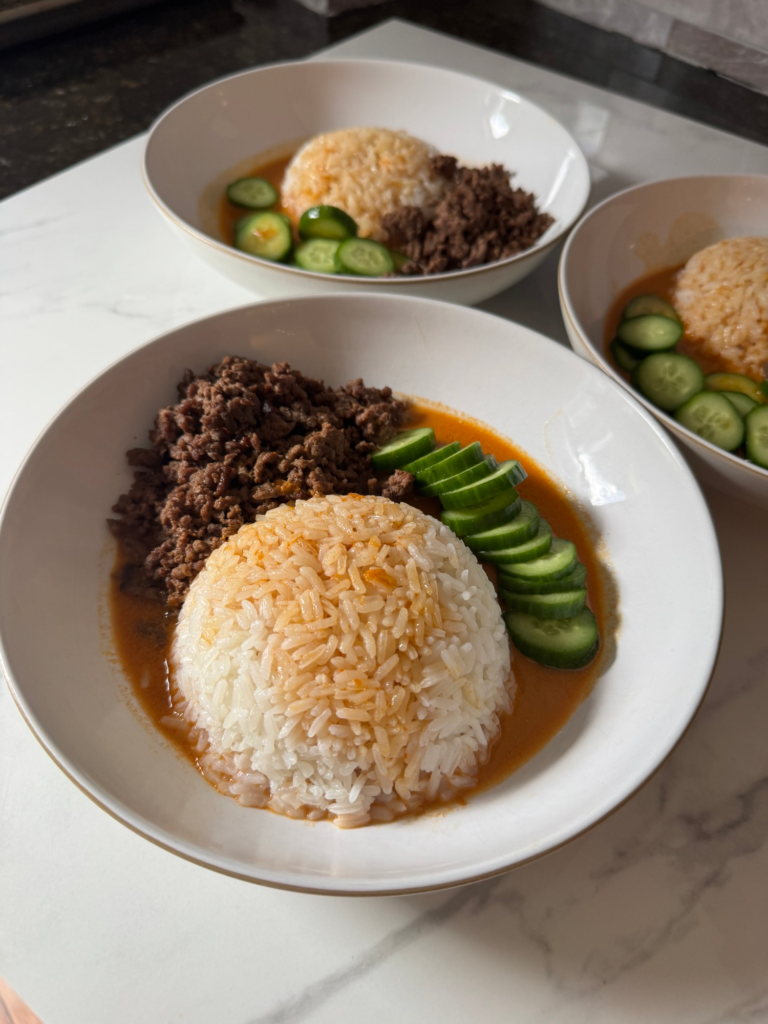 Three brothy beef bowls with rice, beef, and cucumber in coconut curry broth