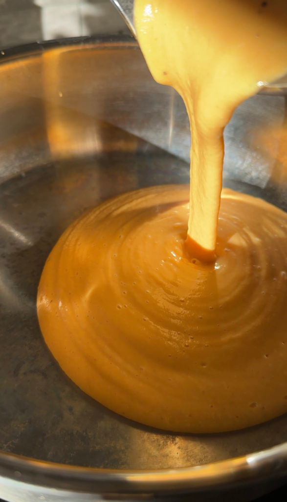 Creamy blended butternut squash cheese sauce being poured