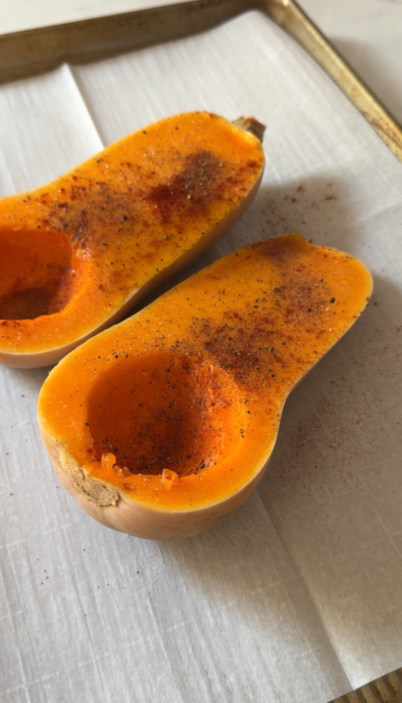 Seasoned butternut squash halves with smoked paprika before roasting