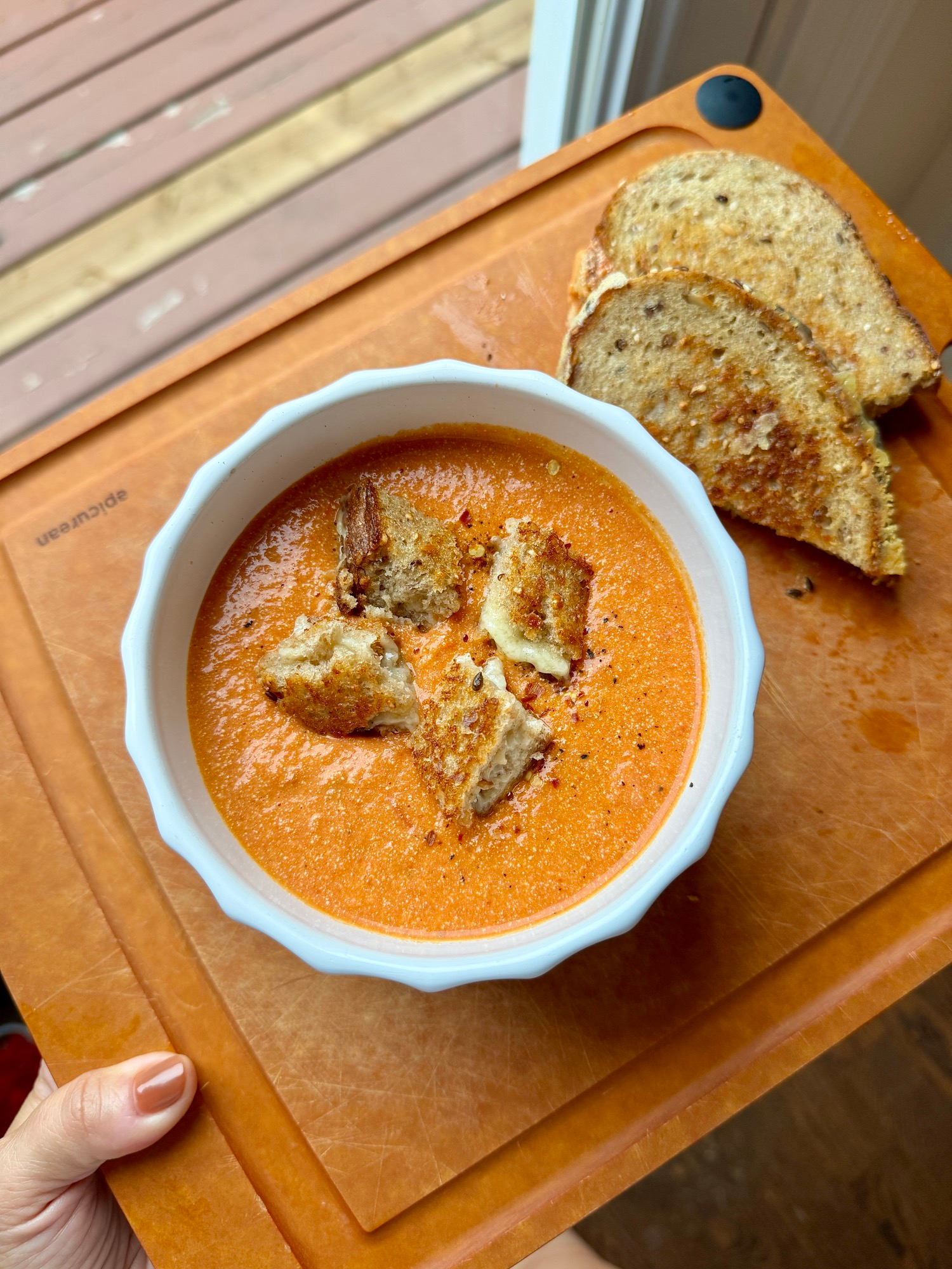 A bowl of creamy roasted tomato soup topped with grilled cheese croutons