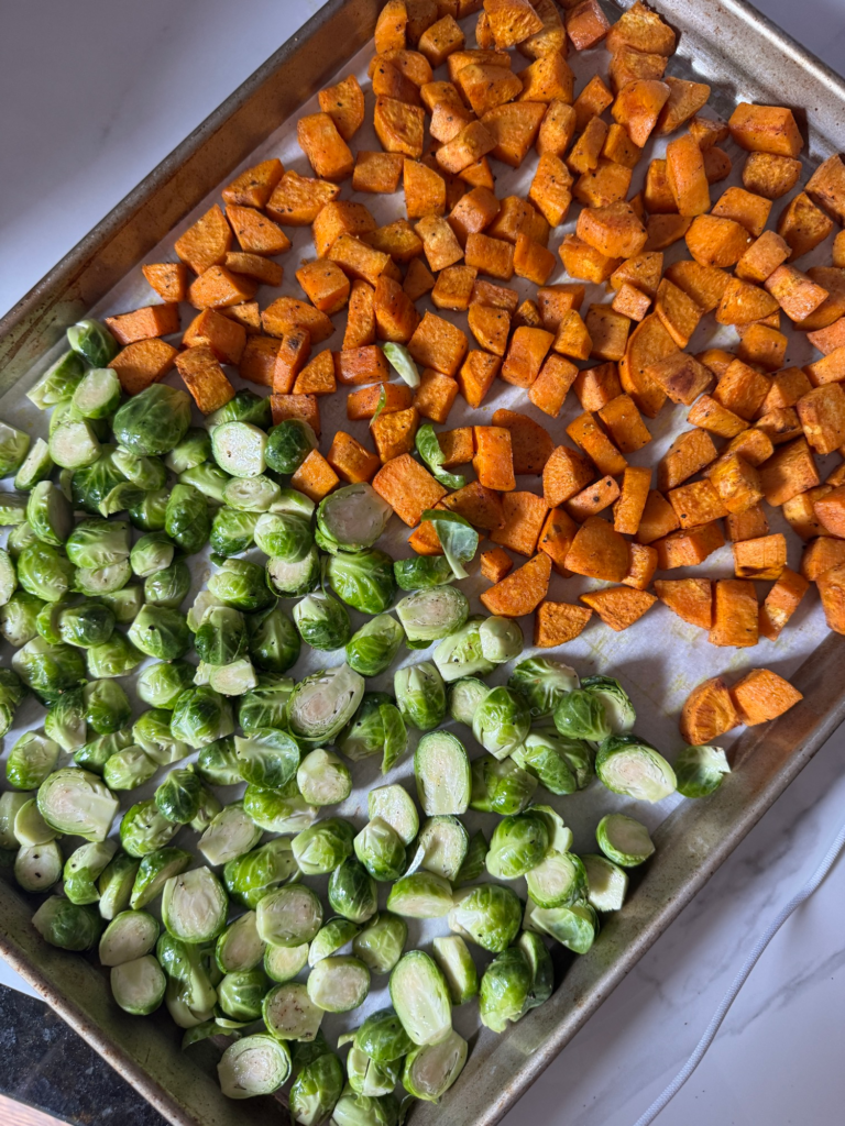 Diced sweet potatoes and halved Brussels sprouts on a sheet pan