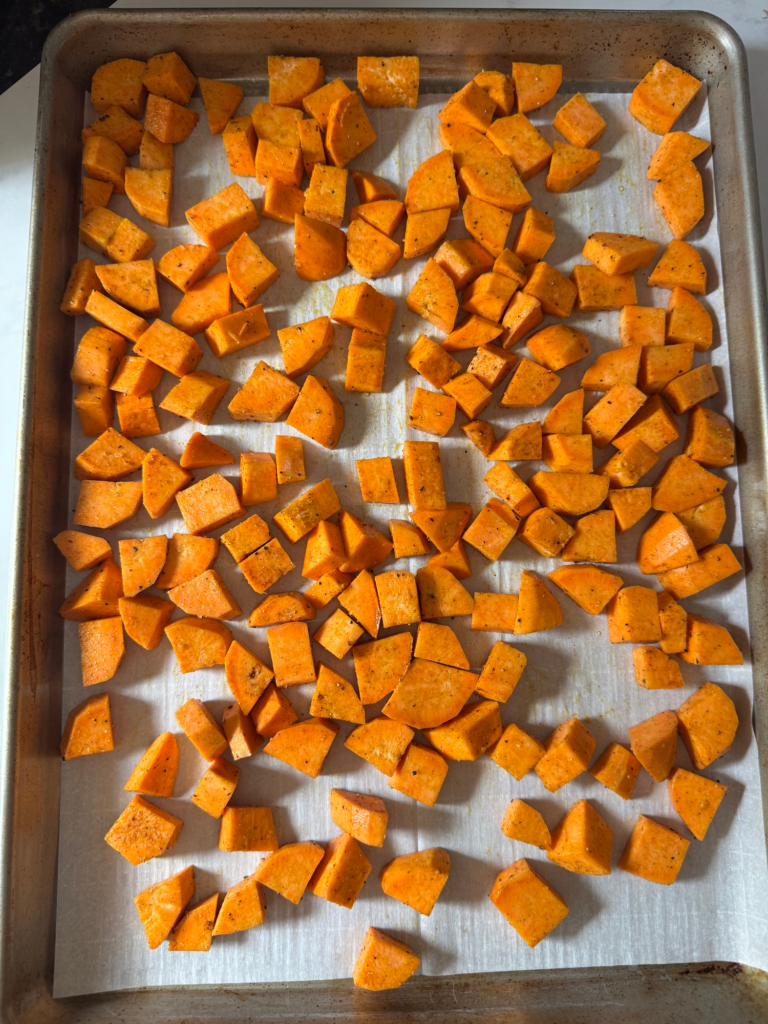 Seasoned diced sweet potatoes on a lined baking sheet