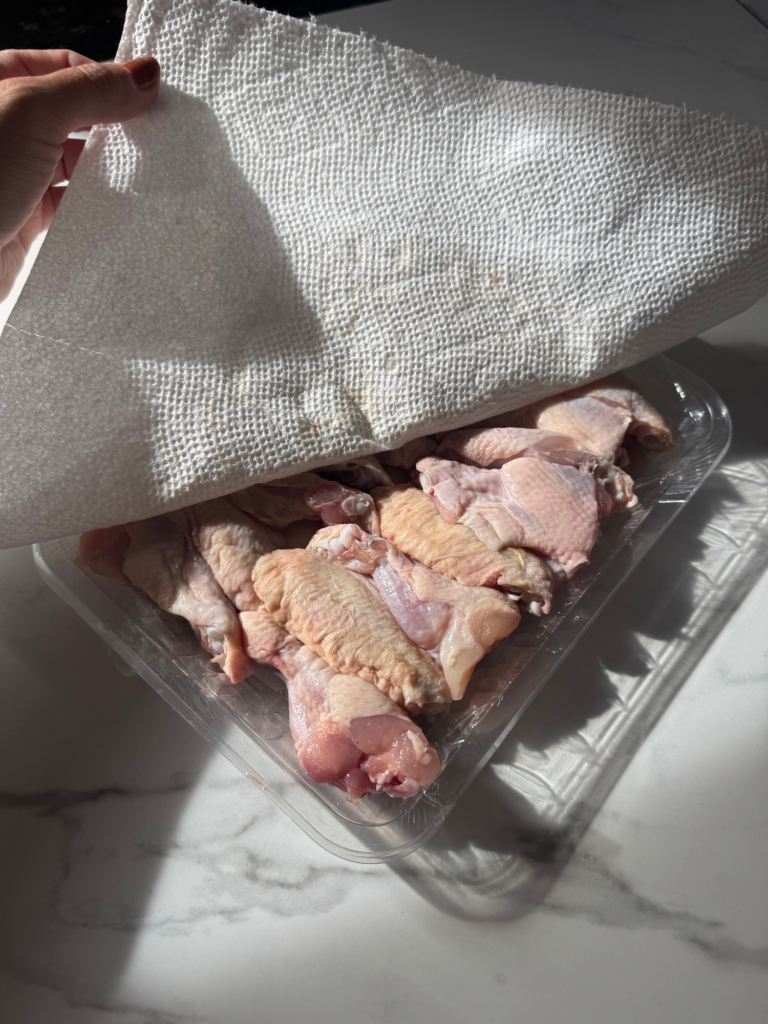 Patting chicken wings dry with a paper towel