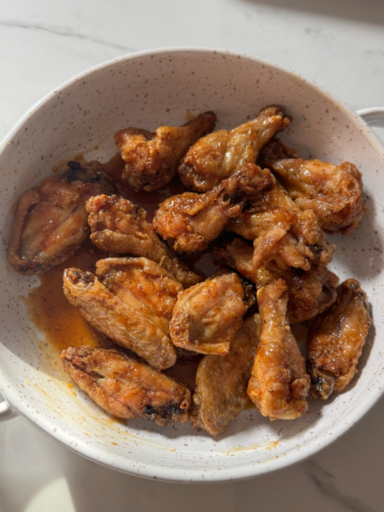 Crispy wings tossed in honey garlic glaze in a bowl