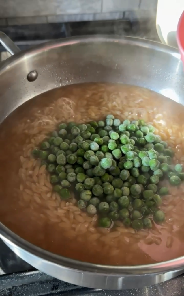 Frozen peas added to simmering orzo