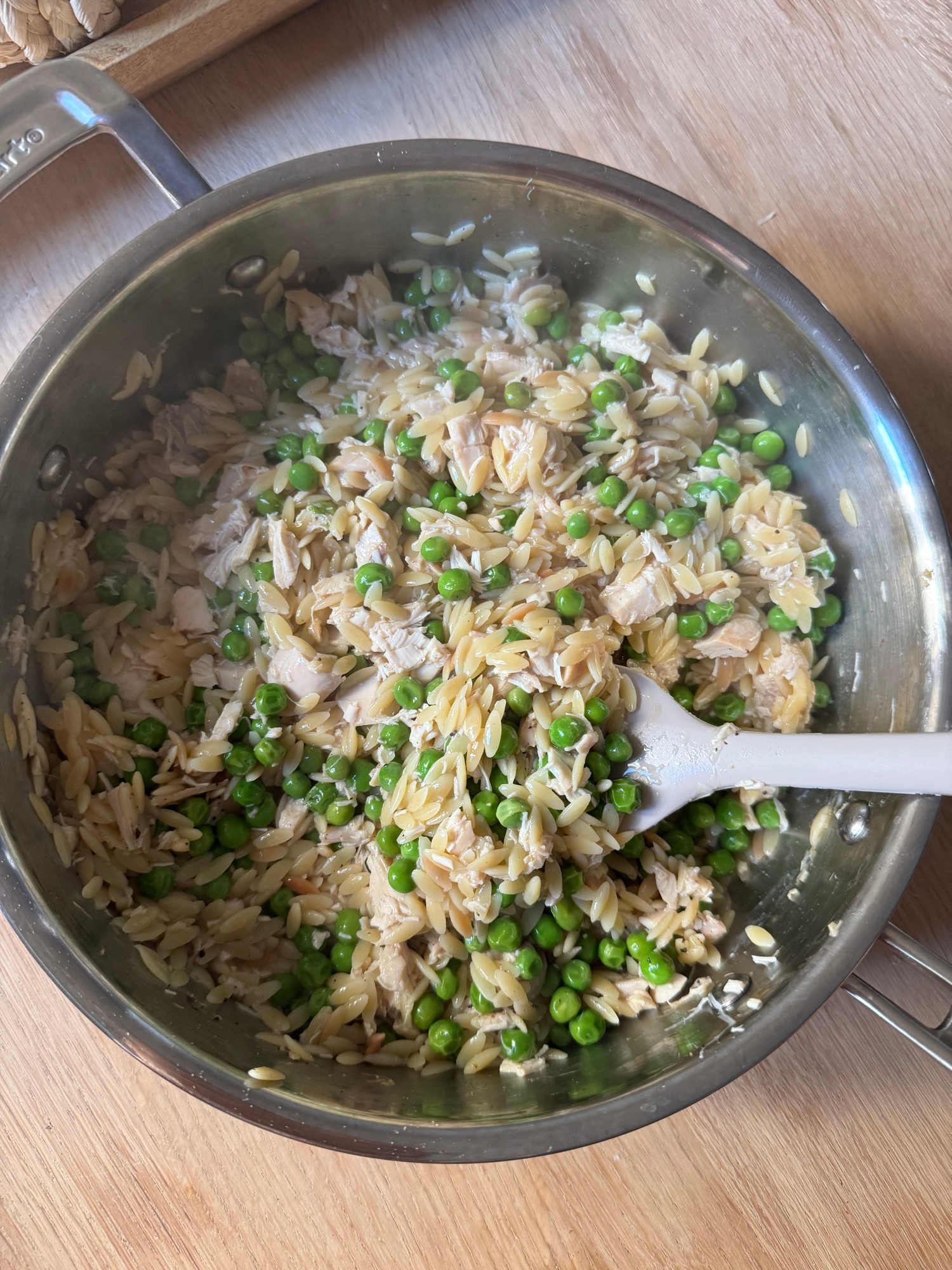Peas and parmesan orzo with rotisserie chicken in a skillet