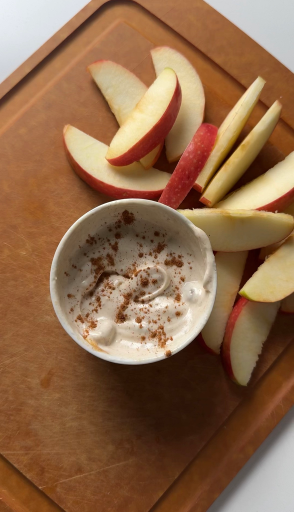 A bowl of creamy protein apple dip with cinnamon and sliced apples