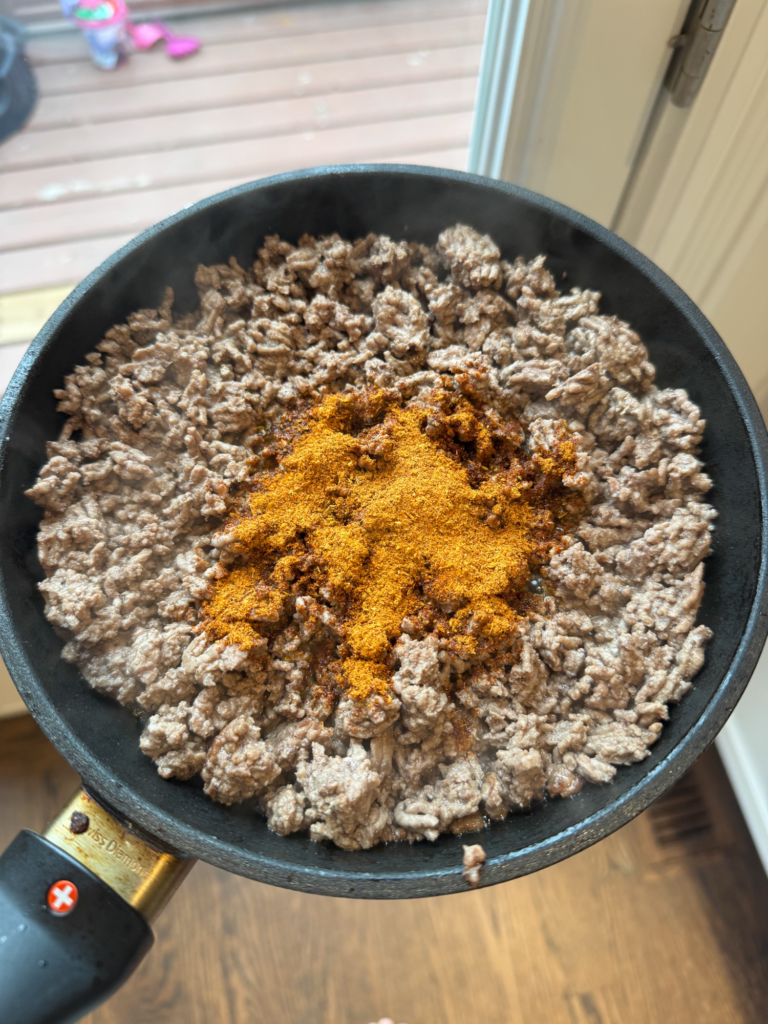 Ground beef in a skillet topped with taco seasoning