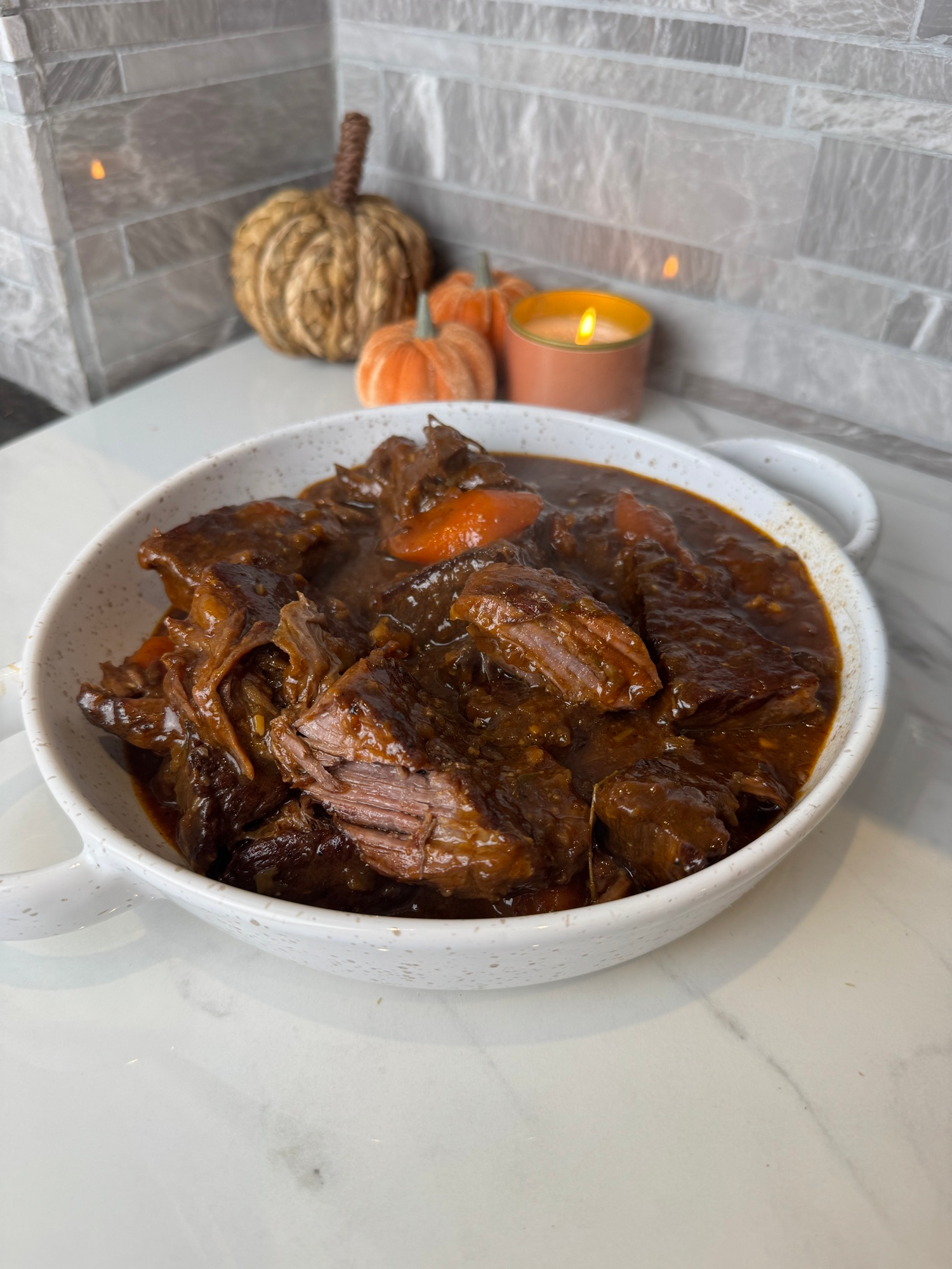 Apple cider braised beef ribs in a white serving bowl