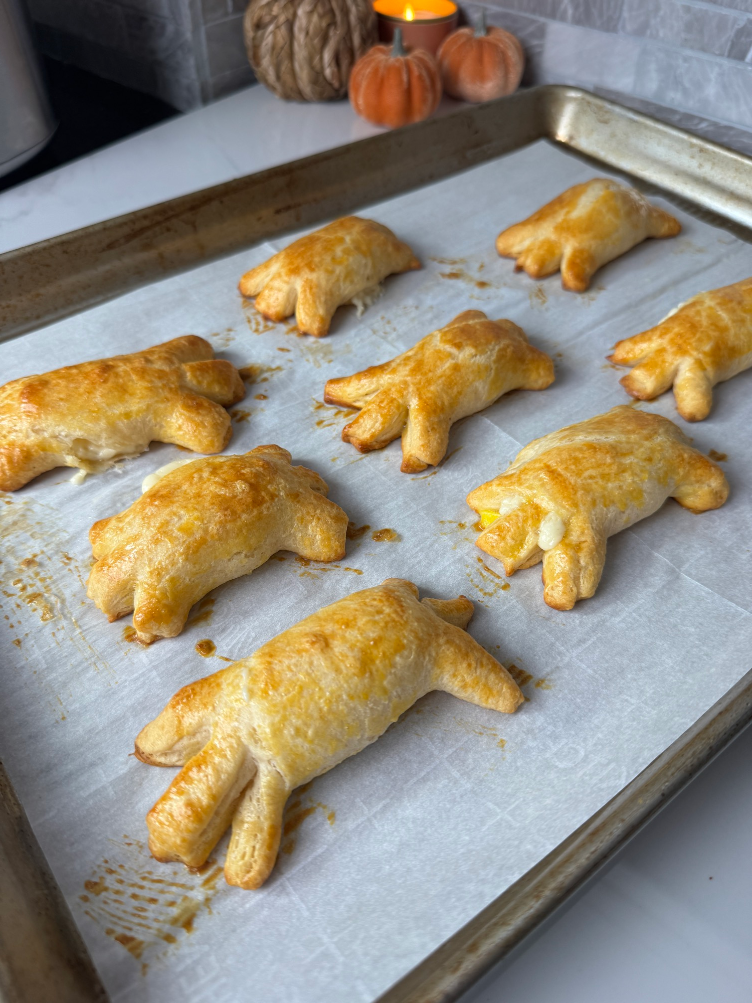 Golden baked mozzarella spiders on a parchment lined baking sheet