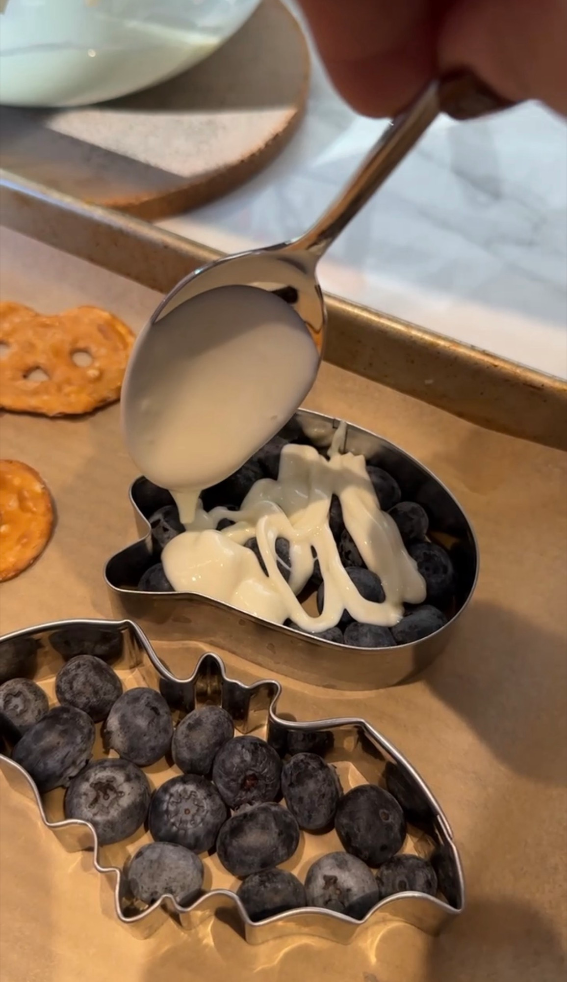 White chocolate spooned over blueberries in ghost and bat cookie cutters